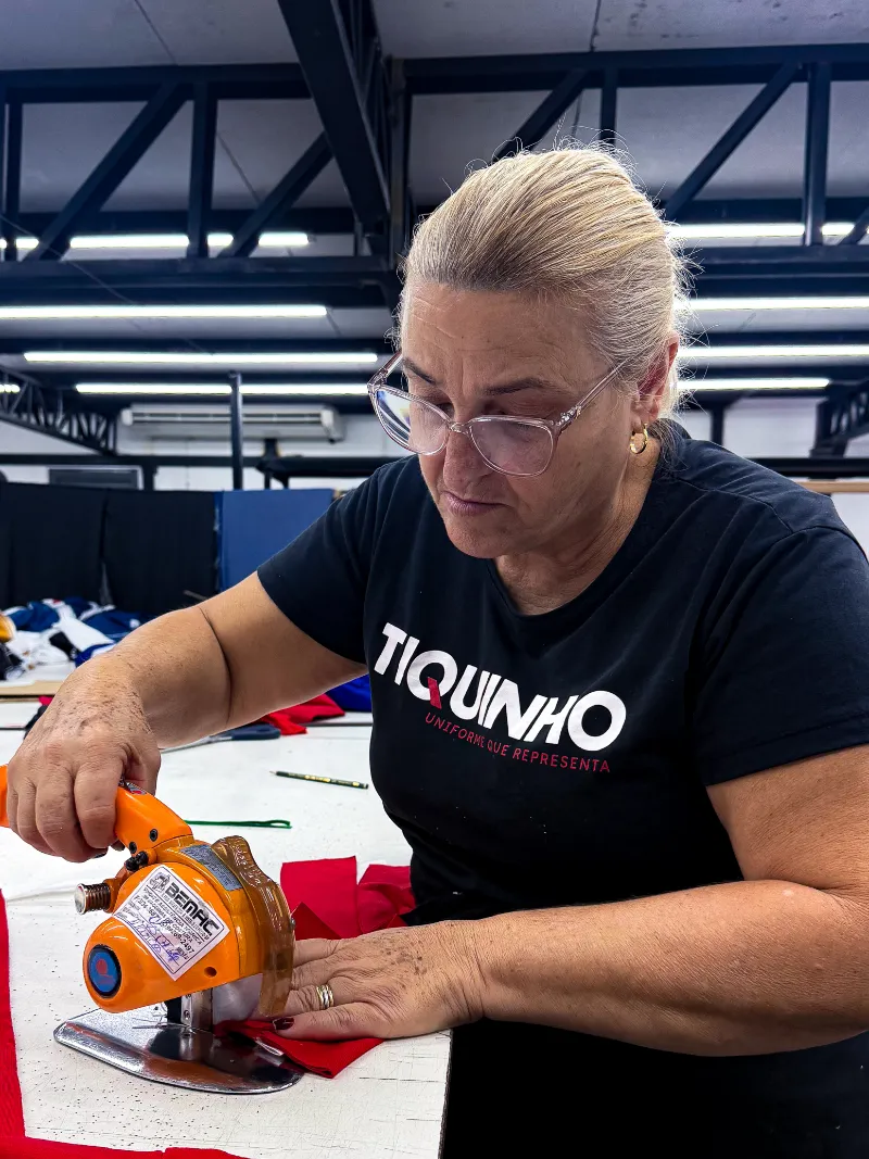Profissional da Tiquinho realizando o corte de tecidos na produção interna
